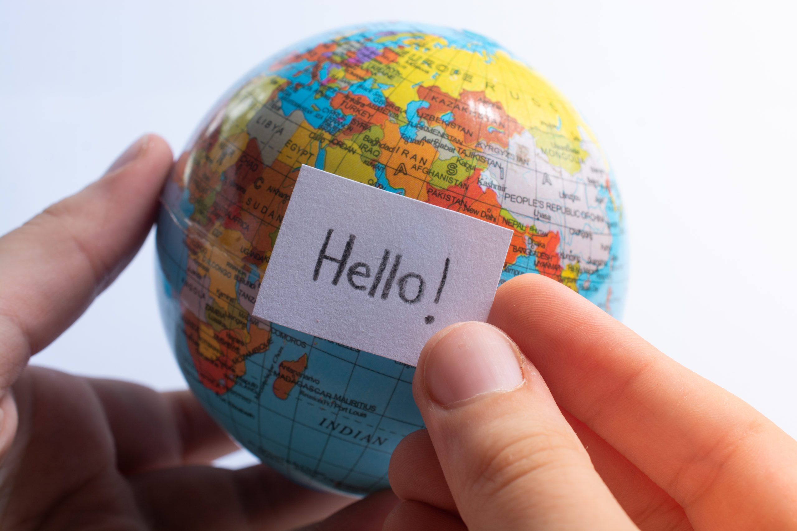 Hand holding notepaper with HELLO wording on model globe